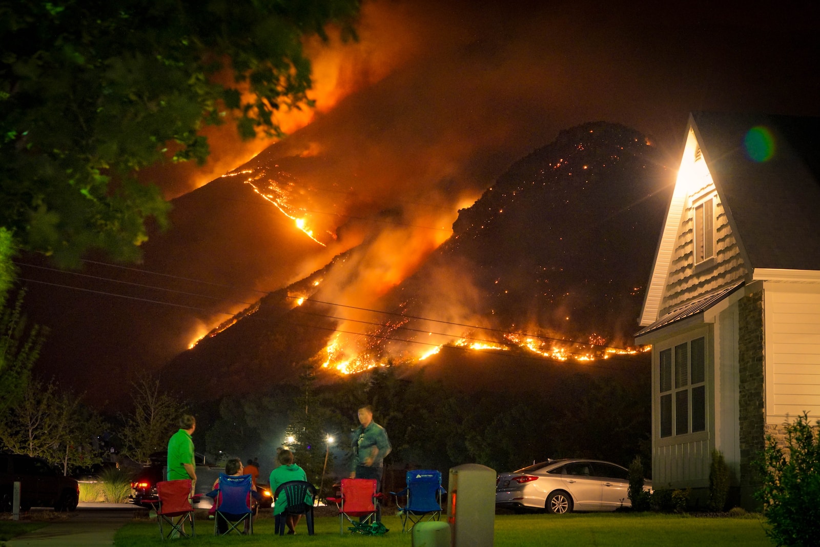 a group of people sitting in lawn chairs in front of a fire